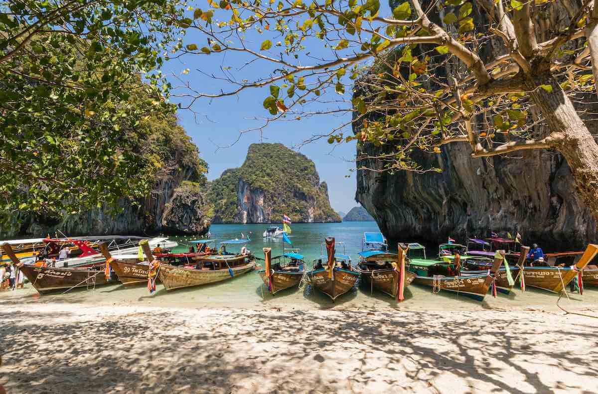 Små båtar på strand i Krabi, Thailand. En populär plats att resa till på vintern.
